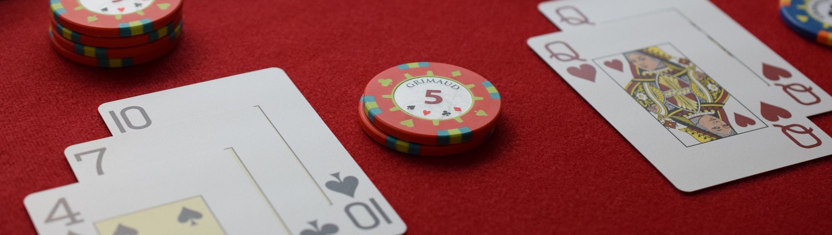 Blackjack-bord med kort og sjetonger på rødt klæde
